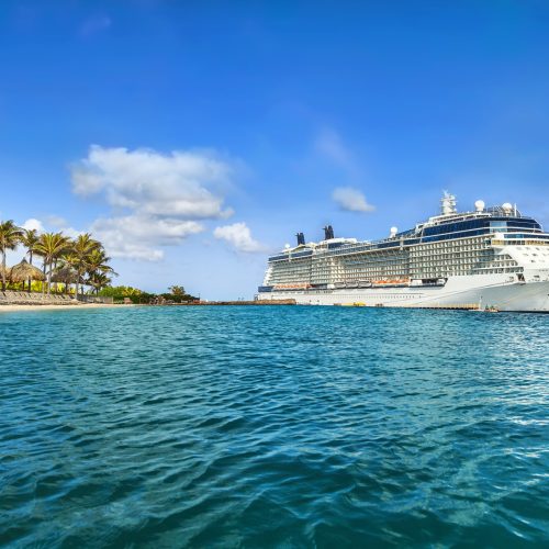 Cruise ship docked at tropical island on sunny day